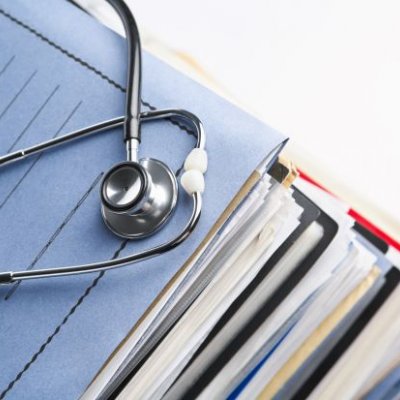 a stethoscope sits on top of a pile of files